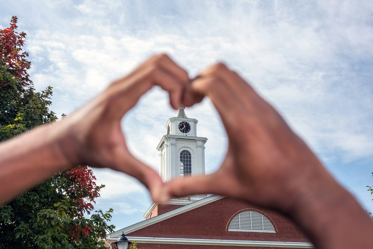 hands forming a heart around a building on campus